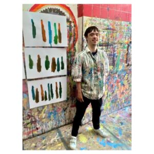 Ein Mann steht vor eine bunten Wand mit Kunstwerken