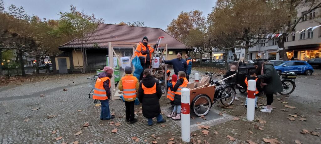 Eine Gruppe von Kindern steht um einen Käfig voller Müll herum.