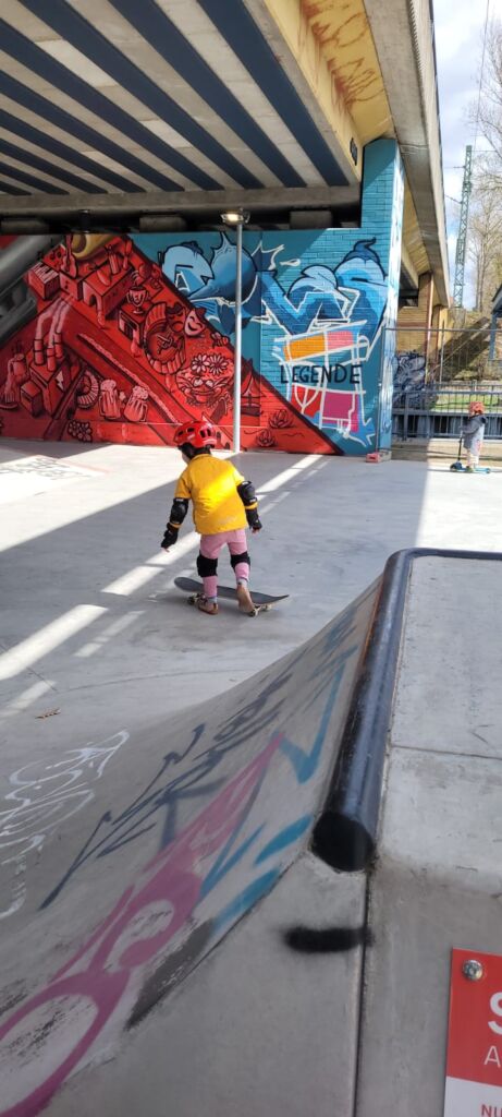 Ein kleines Mädchen auf einem Skateboard.